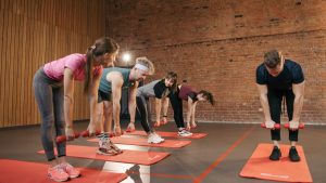 Fitness group performing exercises with dumbbells in a modern yoga studio setting.